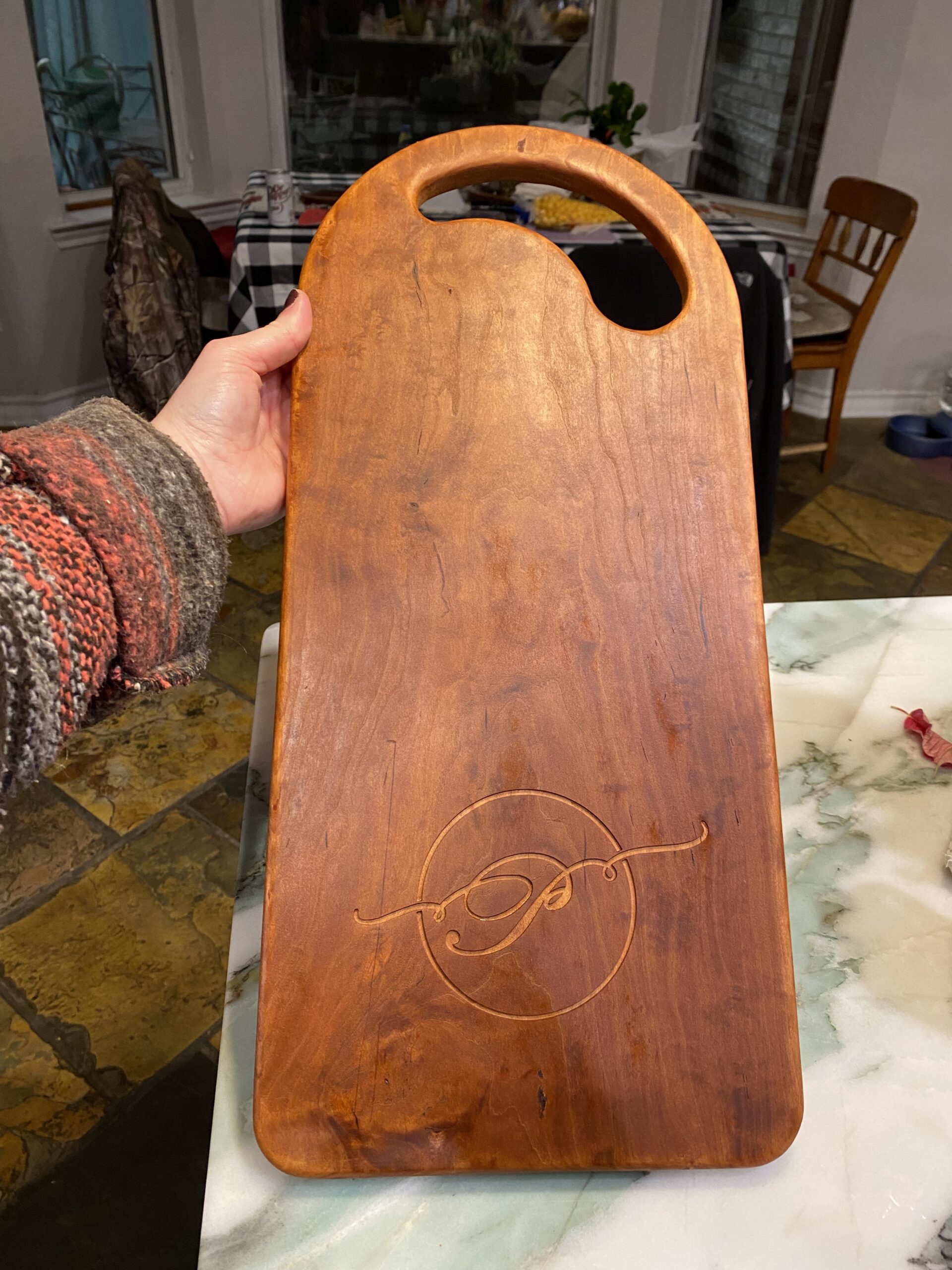 a charcuterie board with a rounded top and rounded bottom corners, with a cursive P carved into it